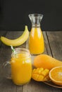 Mango and orange juice in mason jar and slice of tropical fruits on wooden table. Fresh healthy tropical drink. Royalty Free Stock Photo