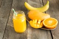 Mango and orange juice and slice of orange on wooden table. Fresh healthy tropical drink. Close up. Royalty Free Stock Photo