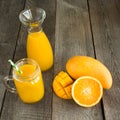 Mango and orange juice and slice of orange on wooden table. Fresh healthy tropical drink. Close up. Royalty Free Stock Photo