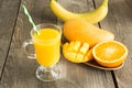Mango and orange juice and slice of orange on wooden table. Royalty Free Stock Photo