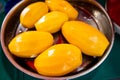 Mango, a photo of fresh yellow mango pile on market table. Ripe tropical fruit closeup. Asian fruit market stall in Thailand.