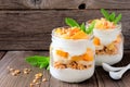 Mango, pineapple parfaits in mason jars on rustic wood