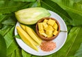 Mango slice on white plate and green leaves from tree tropical summer fruit concept - Ripe mango and green mangoes for snack Royalty Free Stock Photo