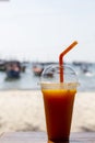 Mango smoothie cocktail with straw on white sand beach. Mango shake in plastic cup Cocktail on sunny seaside. Royalty Free Stock Photo