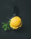 Mango sorbet ice cream scoop in scooper over black background