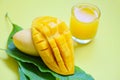 Mango summer juice in glass with sweet ripe slice of mango on green leaves from tree tropical fruit Royalty Free Stock Photo