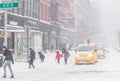 The big snow storm in the street of Manhattan. Cold windy snowy winter day. A few people walking in the street. Traffic lights an