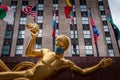 The golden Prometheus statue at the Lower Plaza of Rockefeller center covered with a face mask during the pandemic.  Flags of Amer Royalty Free Stock Photo