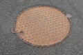Manhole cover, rusty metal lid asphalt road Royalty Free Stock Photo