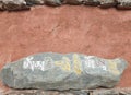 Mani stone placed on the wall. Carved stone with Tibetan script. Royalty Free Stock Photo