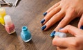 Manicure. Closeup of a woman hand painting her nails with nail polish on a wooden Royalty Free Stock Photo