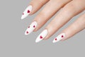 Manicure female hand with gel polish white long nails and red hearts design on a gray background Royalty Free Stock Photo