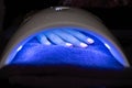 Manicure, getting acryllic nails done under ultraviolet light Royalty Free Stock Photo