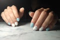 Manicure with glossy blue solid coating and marble design.