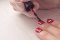 Manicure master paints the nails of the client. Manicurist with a brush paint your nails in red.