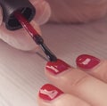 Manicure master paints the nails of the client. Manicurist with a brush paint your nails in red.