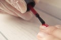 Manicure master paints the nails of the client. Manicurist with a brush paint your nails in red.