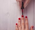 Manicure master paints the nails of the client. Manicurist with a brush paint your nails in red.