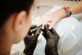 Manicure master wearing black gloves coloring nails for teenager