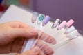 Manicure and nail care concept. A woman in a beauty salon holds colored test nail polishes with different colors and chooses the Royalty Free Stock Photo