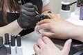 Manicure procedure in a beauty salon. Master in black gloves and the hands of the client. Personal care and cosmetics. Close-up