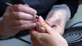 Manicure procedure the master displaces the remnants of dirt from under the nail with a wooden stick