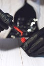 Manicure specialist in black gloves holding a bottle with red gel nail varnish. Close up of red gel nail polish. Manicurist in