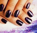 Manicure stylish concept: woman fingers with nails purple glitter on nails like cosmos, universe background Royalty Free Stock Photo
