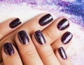 manicure stylish concept: woman fingers with nails purple glitter on nails like cosmos, universe background Royalty Free Stock Photo