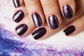 Manicure stylish concept: woman fingers with nails purple glitter on nails like cosmos, universe background Royalty Free Stock Photo