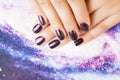 Manicure stylish concept: woman fingers with nails purple glitter on nails like cosmos, universe background Royalty Free Stock Photo