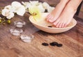 Manicured female feet in spa wooden bowl with flowers and water closeup Royalty Free Stock Photo