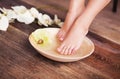 Manicured female feet in spa wooden bowl with flowers and water closeup Royalty Free Stock Photo