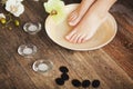 Manicured female feet in spa wooden bowl with flowers and water Royalty Free Stock Photo