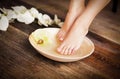 Manicured female feet in spa wooden bowl with flowers and water Royalty Free Stock Photo