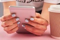 Manicured hands holding pink smartphone.