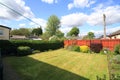 Manicured lawn of a back garden with cloudy blue skies above