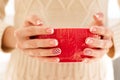Woman& x27;s hands with french manicure and candy cane pattern on the nails. Woman with beautiful manicure holding big red Royalty Free Stock Photo