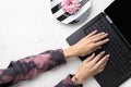 Manicured woman`s hands in trendy pink hoodie typing on laptop