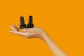 Manicured womans hand holding nail varnish bottle on orange background. Beauty salon template Royalty Free Stock Photo