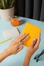 Manicured womans hands holding note pad over blue table. Back to school work from home concept