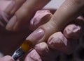 The manicurist applies a base layer to the client`s nail.Applying a transparent varnish with a brush.