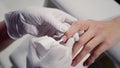 Manicurist applies cover hardener on customer nail with brush in cosmetology salon closeup