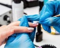 Manicurist applies a layer of gel polish to the clientÃ¢â¬â¢s nail. Brush pink nail polish