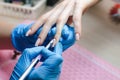 Manicurist applies a layer of gel to the nail with a brush, close-up