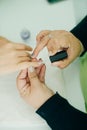 Manicurist applying cuticle softener or clear nail varnish to the fingernails of a lady client in a spa or beauty salon Royalty Free Stock Photo