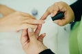 Manicurist applying cuticle softener or clear nail varnish to the fingernails of a lady client in a spa or beauty salon Royalty Free Stock Photo