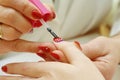 Manicurist applying red nail