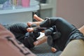 Manicurist in black gloves makes a cut manicure, trimming the cuticle with scissors Royalty Free Stock Photo