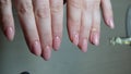 manicurist in black gloves paints nails in beige neutral color close-up beauty salon manicure process with gel polish